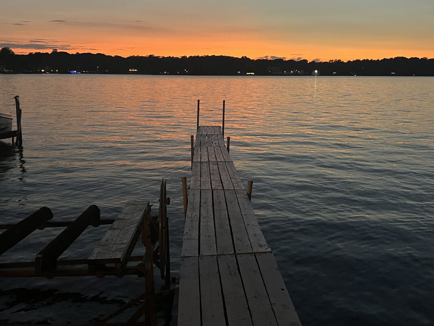Old wooden pier at dusk with orange sky over the Chain O'Lakes